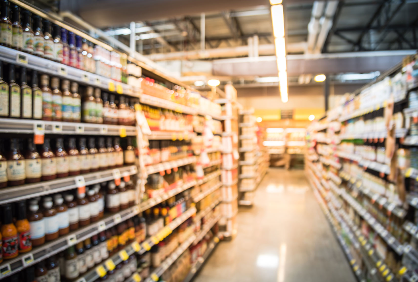 Blur selection of salad dressing, pickles, condiments, and canned beans/veggies/soups on shelves in store (Getty Images/TrongNguyen)