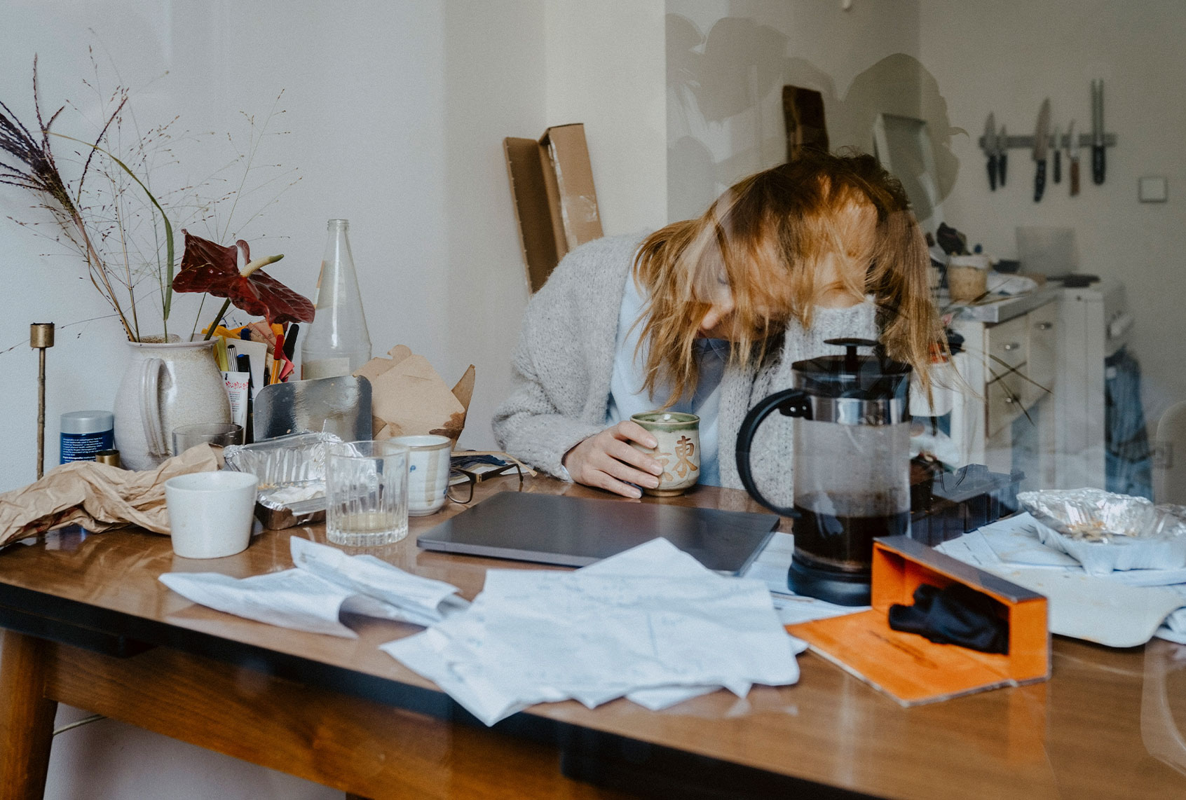 Emotionally stressed businesswoman with coffee cup at table in living room (Getty Images/Maskot)