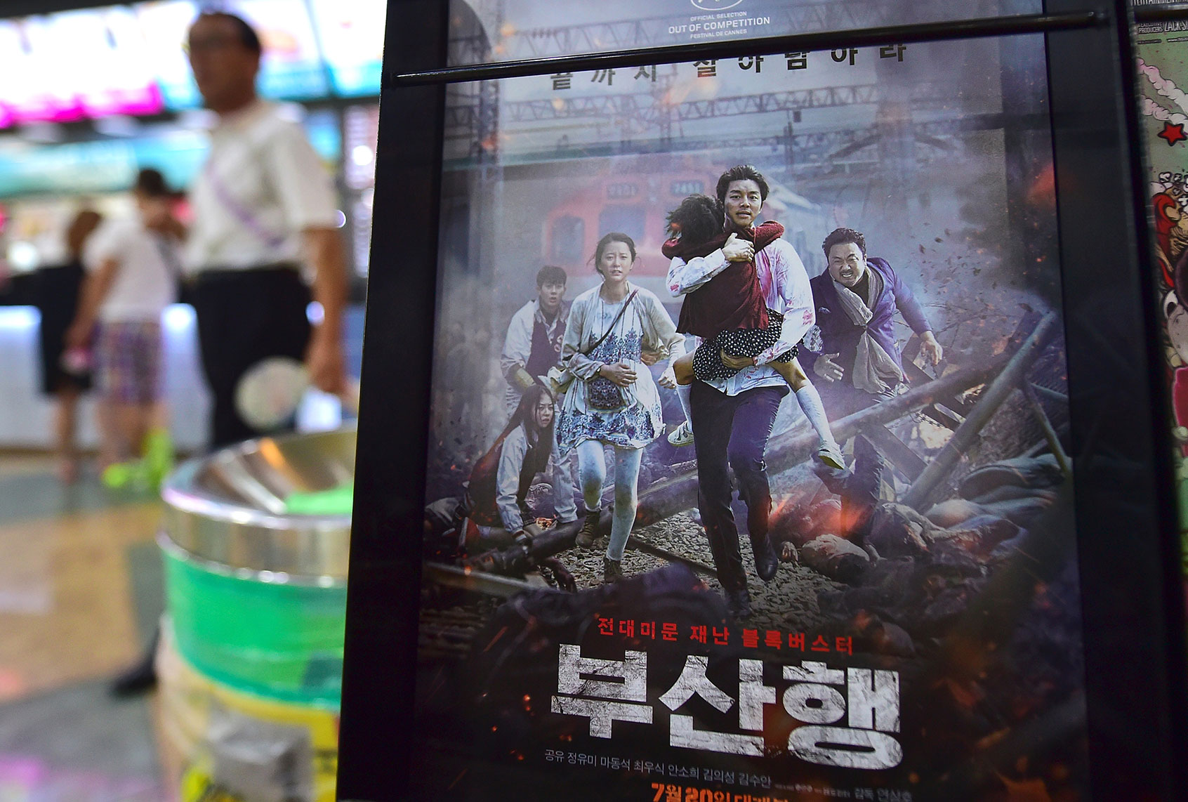 A man walks past a poster of the first South Korean zombie blockbuster, "Train to Busan," at a movie theater in Seoul on August 4, 2016. (JUNG YEON-JE/AFP via Getty Images)