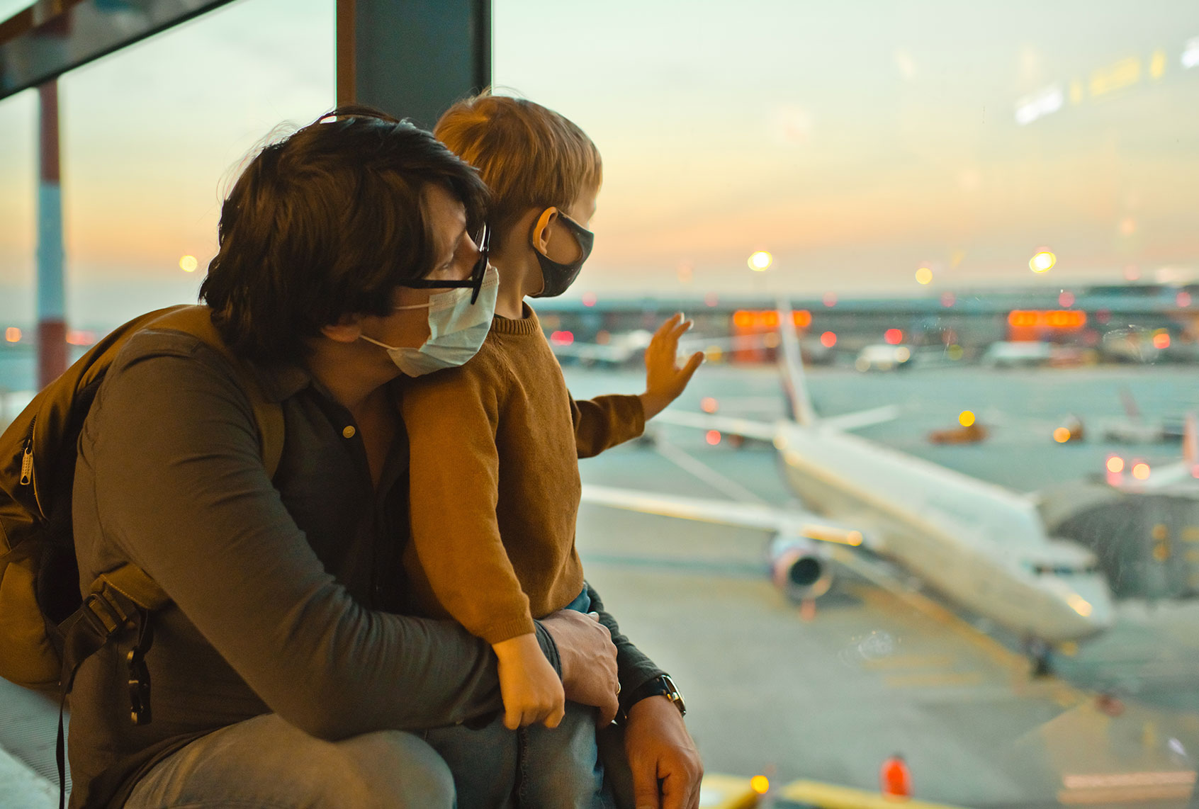Family in protective face masks in airport during COVID-19 pandemic (Getty Images/ArtMarie)