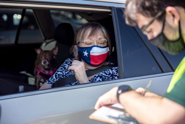 A poll worker helps a voter at a mail in ballot drop off location on October 13, 2020 in Austin, Texas. The first day of voting saw voters waiting hours in line to cast their votes. Gov. Greg Abbott announced earlier this year that he would expand early voting for the election beginning on Oct. 13. Mail in voting began on Oct. 8 and has been part of a legal battle after Gov. Abbott declared each county may only have 1 mail in ballot drop off center, the ruling was later struck down in federal court but then the decision was upheld when a stay was ruled in the overturning. (Sergio Flores/Getty Images)
