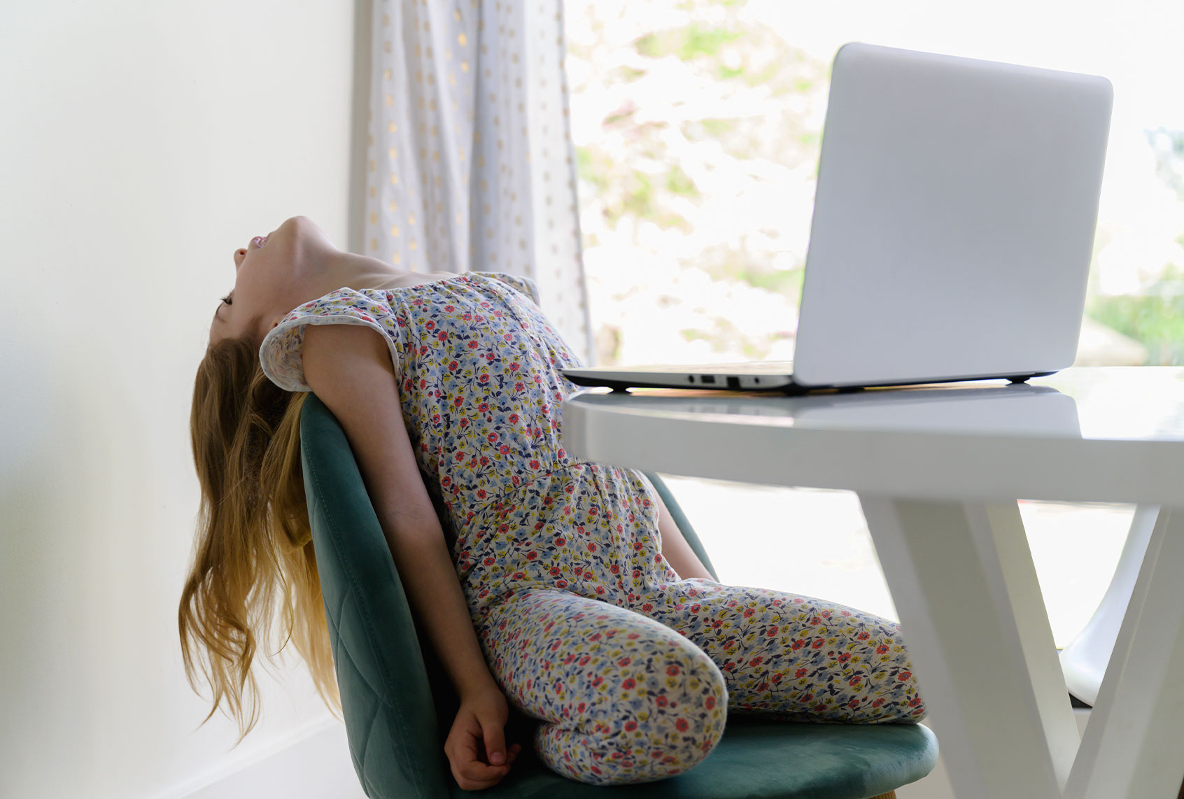 Yong girl leaning back, distracted during at-home learning on computer (Getty Images/Jamie Grill)