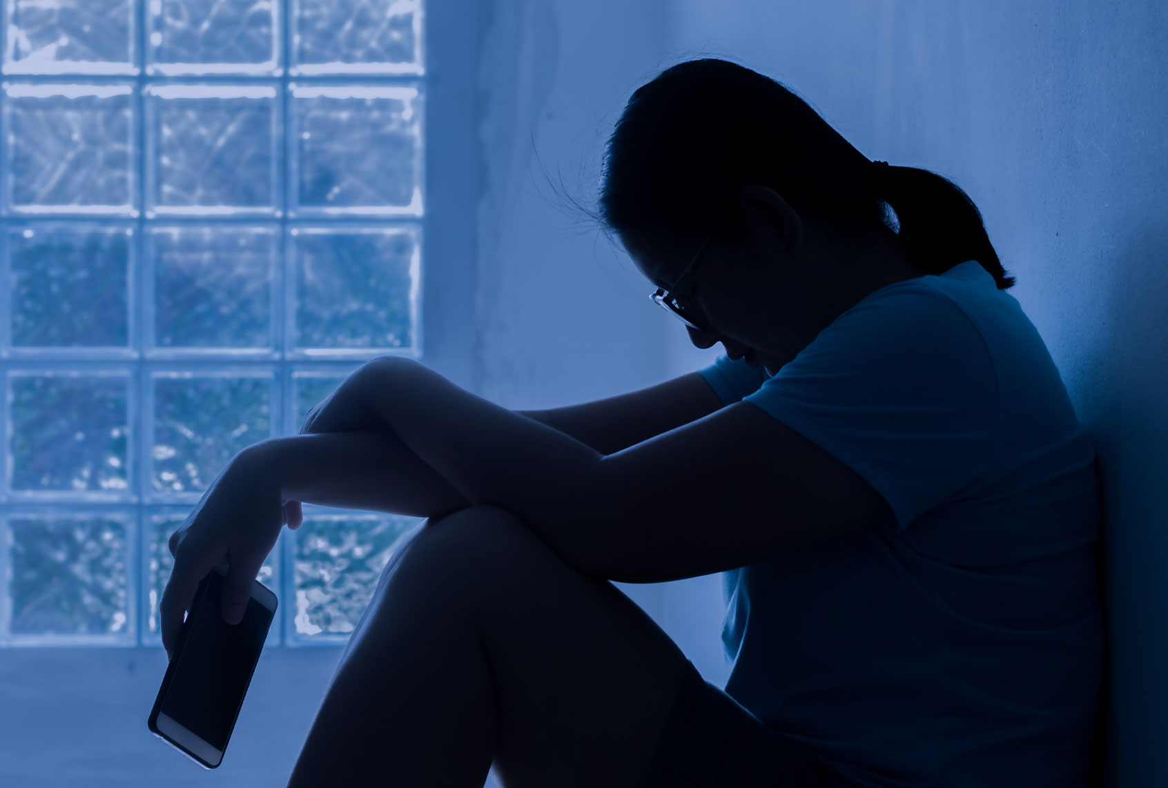 Silhouette Depress Woman Sitting And Hold Smartphone (Getty Images / Krisda Ponchaipulltawee / EyeEm)