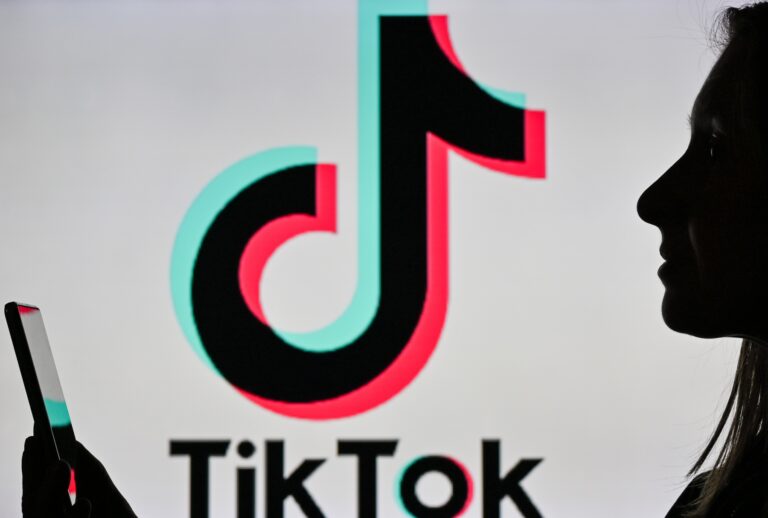 Silhouette of woman looking at phone and Tiktok ( Artur Widak/NurPhoto via Getty Images)