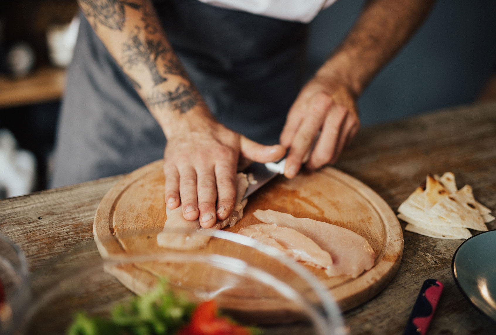 Close up of chef's hands cutting chicken meat on the wooden board (Getty Images/Anchiy)