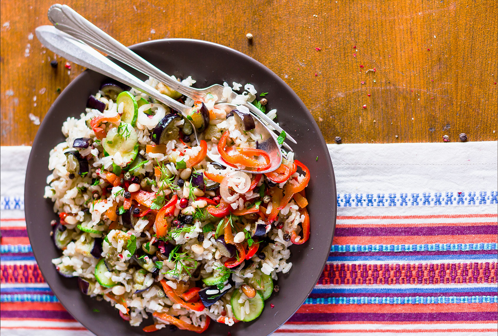 Plate of warm salad with brown rice, roasted eggplant, zucchini, red and green bell pepper, mushroom, and onion (Getty Images/Anna Kurzaeva)