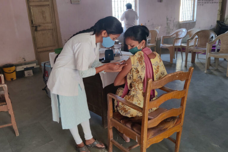 A health worker administers a Covid-19 vaccine to a woman at a vaccination center run by Amgaon Primary Health Center, which serves the tribal villages of the Talasari region in India. (Photo by Puja Changoiwala for Undark.)