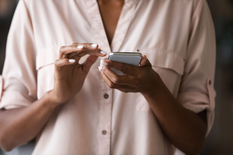 A woman holding a smart phone in her hand, typing a message. (Getty Images/fizkes)