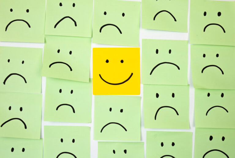 Sad faces on sticky notes with one happy one (Getty Images / mikroman6)