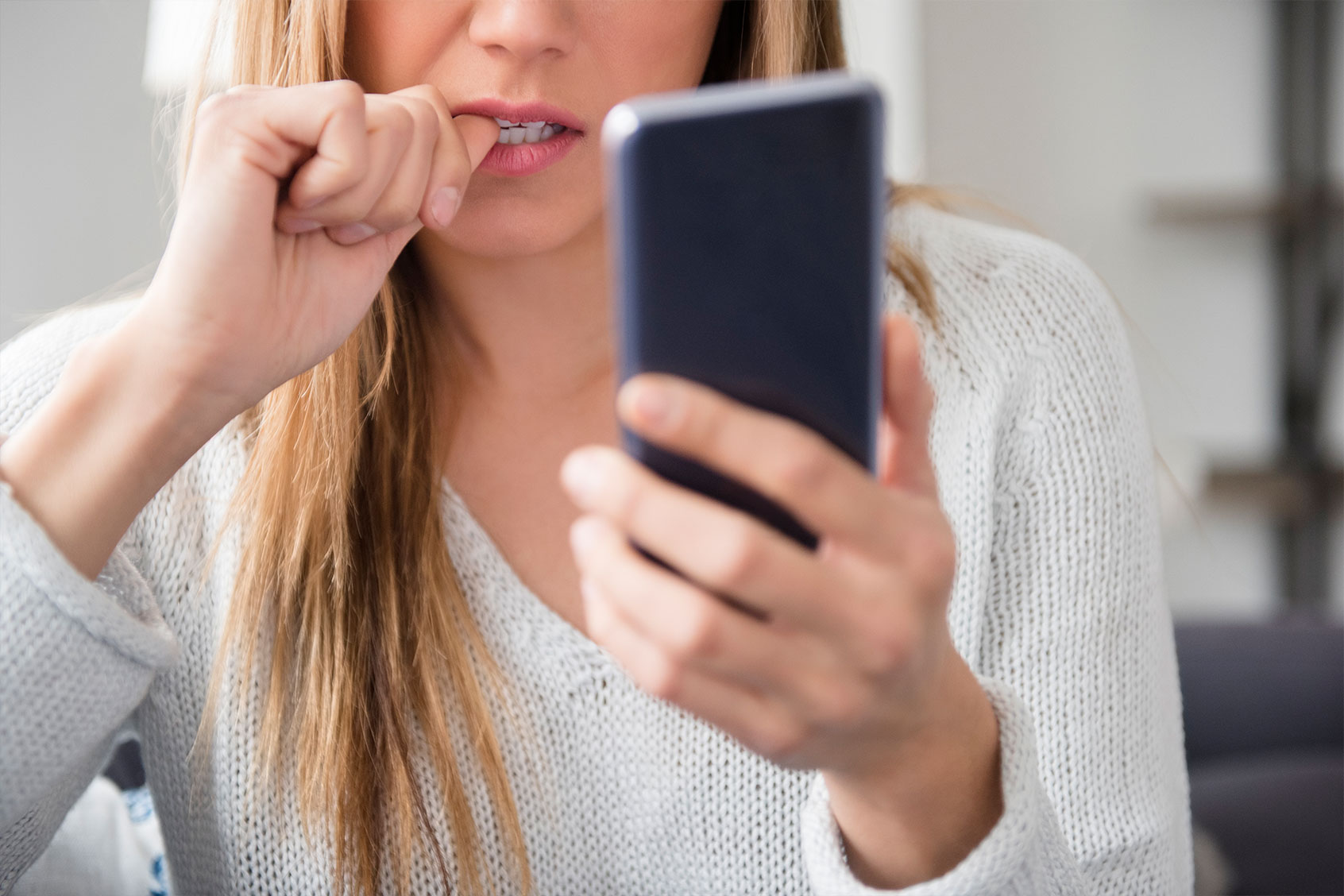 Nervous young woman using smartphone (Getty Images/Jamie Grill)