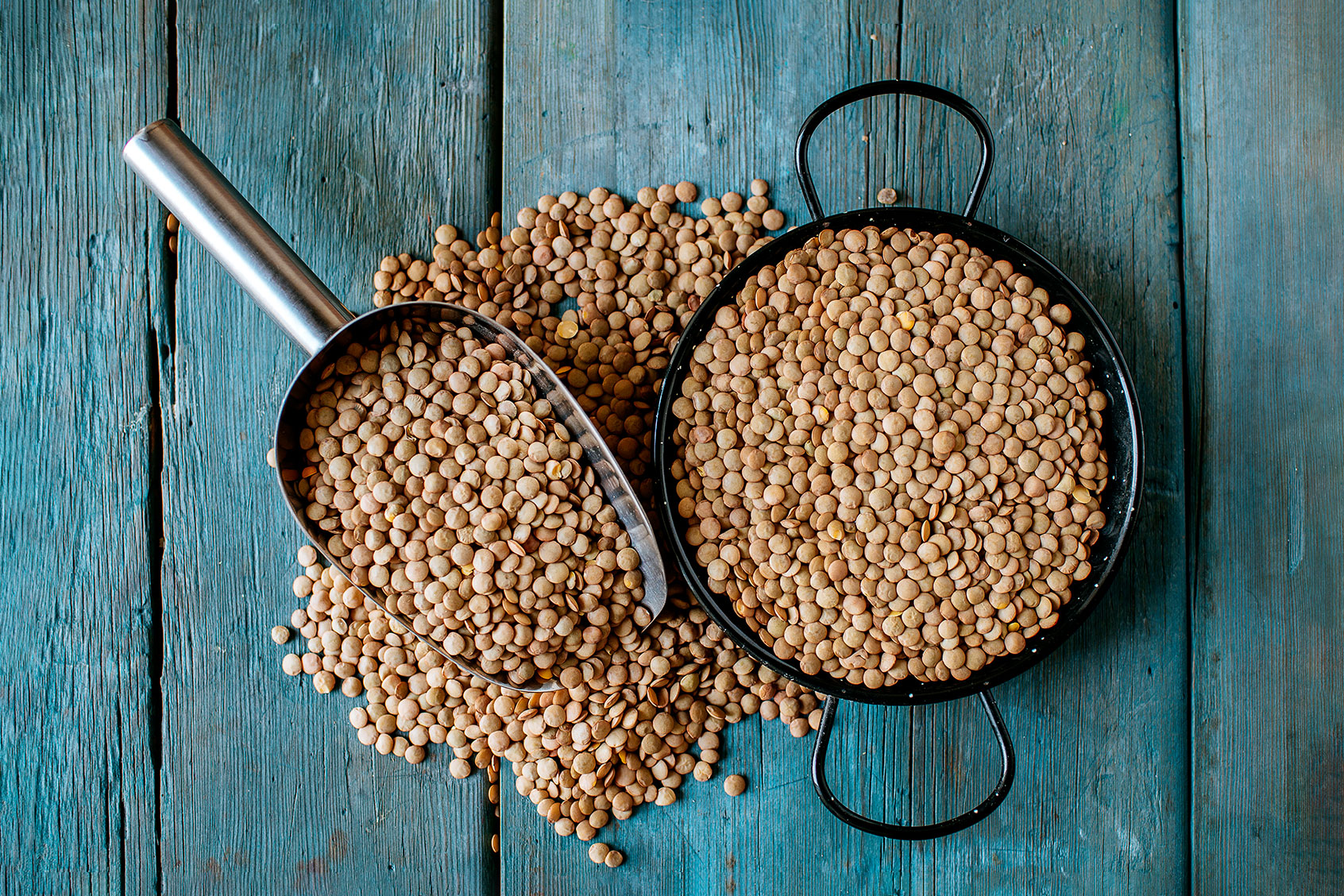 Skillet and metal scoop with dried brown lentils on wood (Getty Images/Westend61)