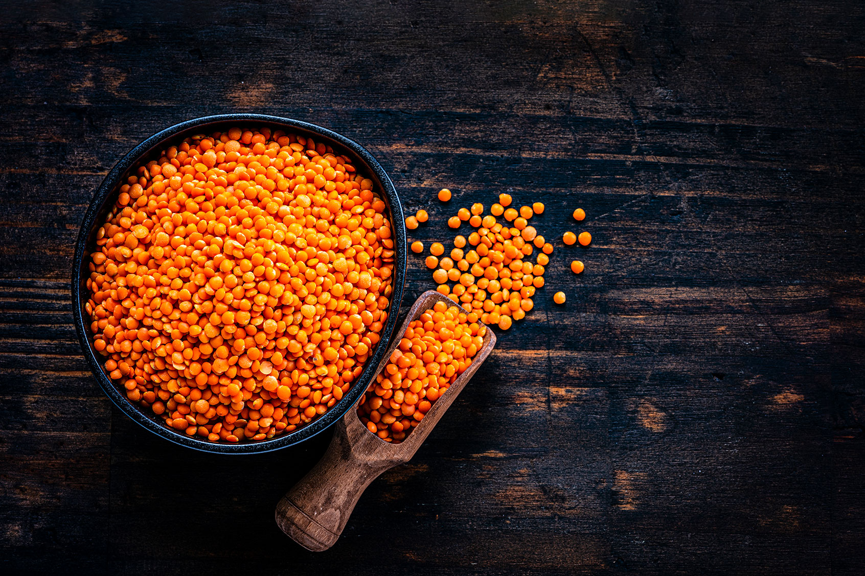 Red lentils in a black bowl shot from above on dark wooden table (Getty Images/fcafotodigital)