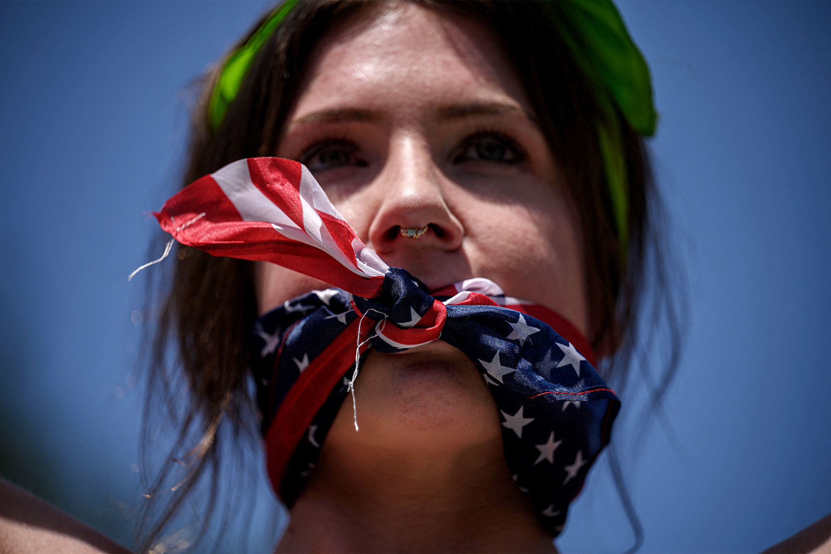 A reproductive rights activist, gagged by a scarf in the colors of the US flag, marches during a protest against a recent Supreme Court ruling on abortion rights, in New York, July 4, 2022. (ED JONES/AFP via Getty Images)