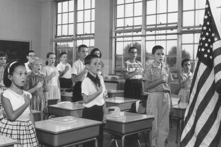 School children holding their hands over their hearts while reciting the Pledge of Allegiance in a classroom. (Lambert/Getty Images)