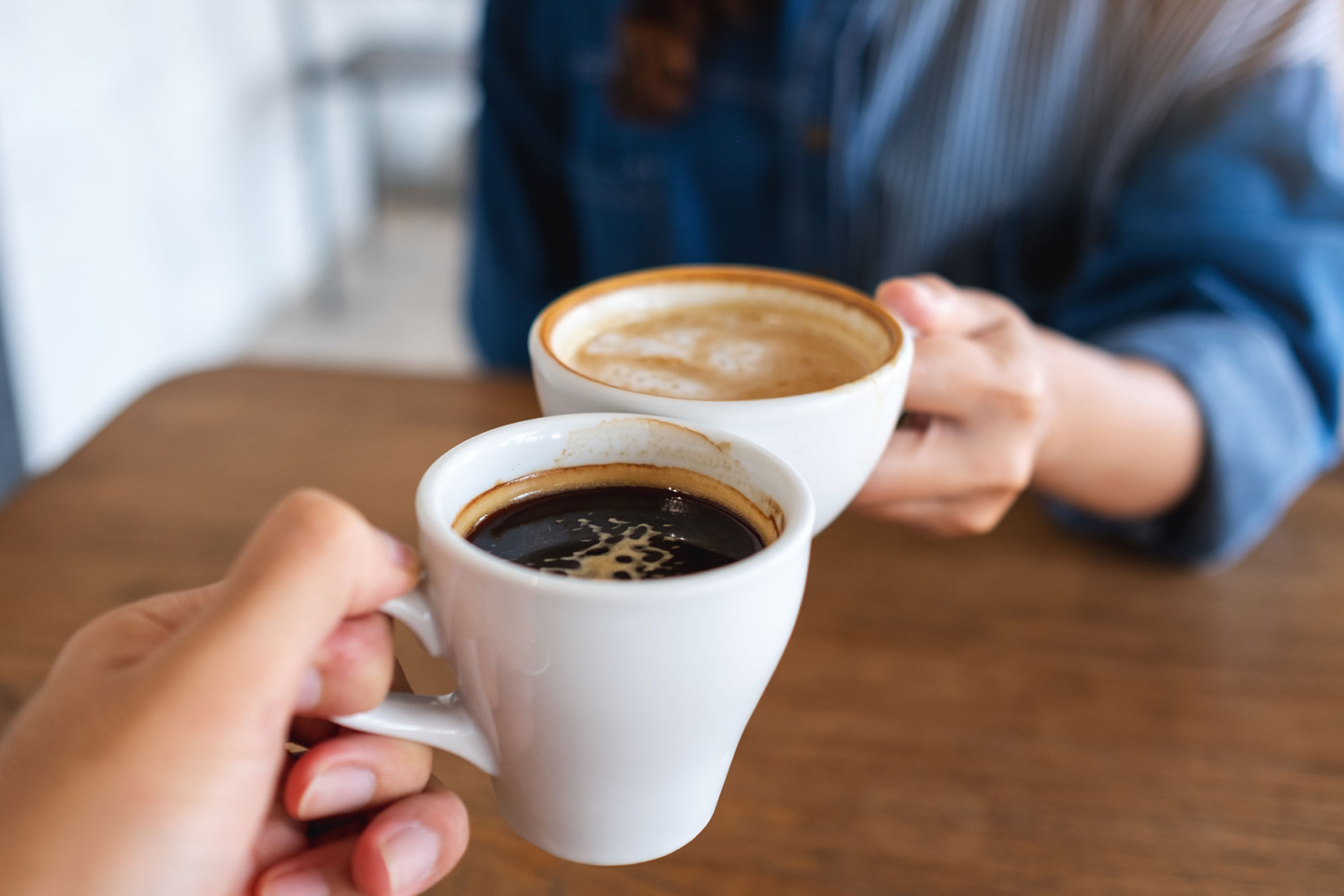 Clinking coffee cups together in cafe (Getty Images/Farknot_Architect)