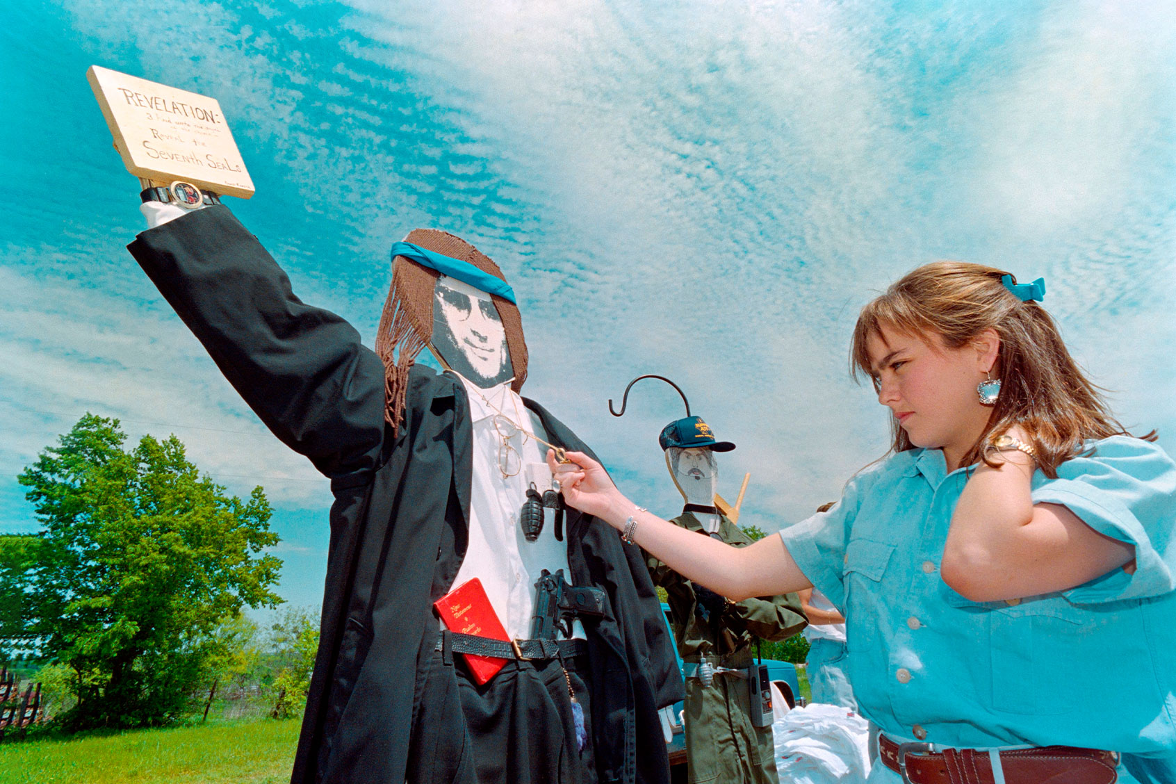 Beth Barham of Corpus Christi looks over a life-size cardboard cutout of Branch Davidian cult leader David Koresh placed on a hill near the Branch Davidian cult compound in Waco on April 16, 1993 as the armed stand-off between the religious cult and federal agents continued. (BOB DAEMMRICH/AFP via Getty Images)