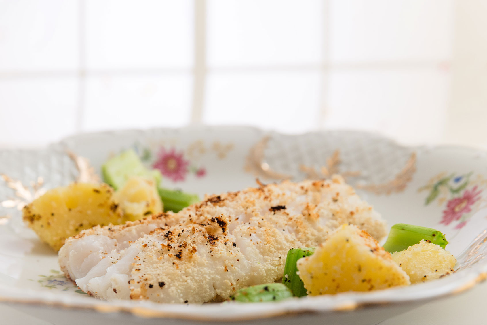 Decorative plate with fried breaded fish, sautéed chopped celery and cooked and fried potatoes (Getty Images/annick vanderschelden photography)
