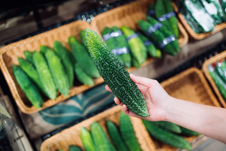 Woman grocery shopping in supermarket and picking a fresh bitter gourd from basket (Getty Images/d3sign)