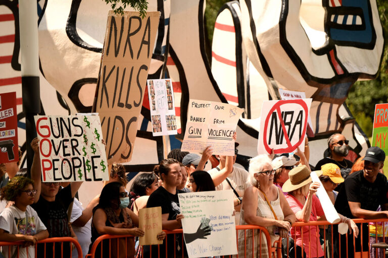 Protesters in support of gun control hold signs accross the National Rifle Association Annual Meeting at the George R. Brown Convention Center, on May 27, 2022, in Houston, Texas. (PATRICK T. FALLON/AFP via Getty Images)