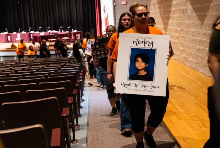 Attendees hold signs as they walk out of a Uvalde Consolidated Independent School District Board special meeting to consider the firing of Police Chief Pete Arredondo on August 24, 2022 in Uvalde, Texas. (Jordan Vonderhaar/Getty Images)