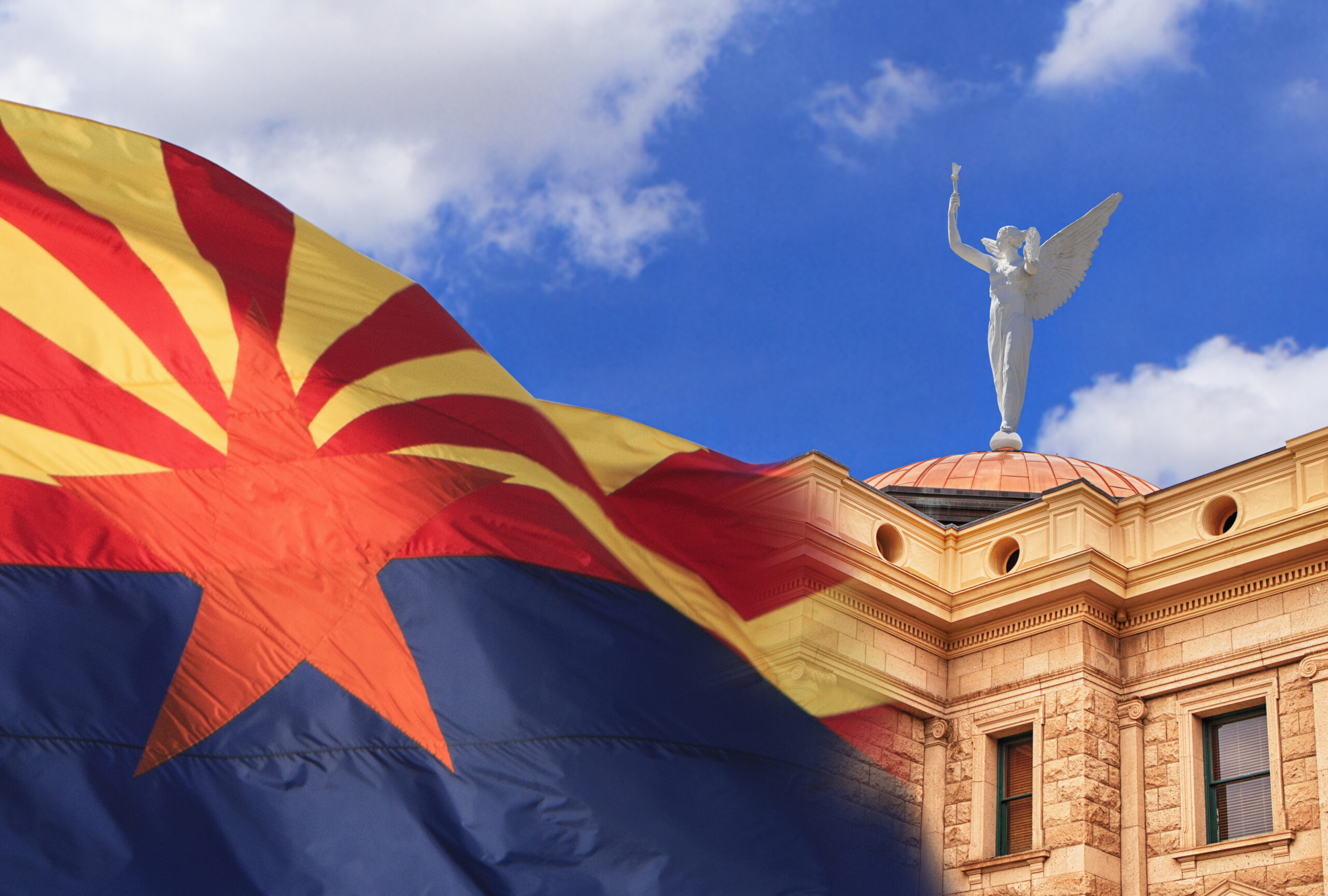 Arizona state capitol building in Phoenix, with wind blowing the state flag outside. Winged Goddess of Victory, Statue of Justice weather vane stands on top of the Capitol's copper dome. (Getty Images / DustyPixel)