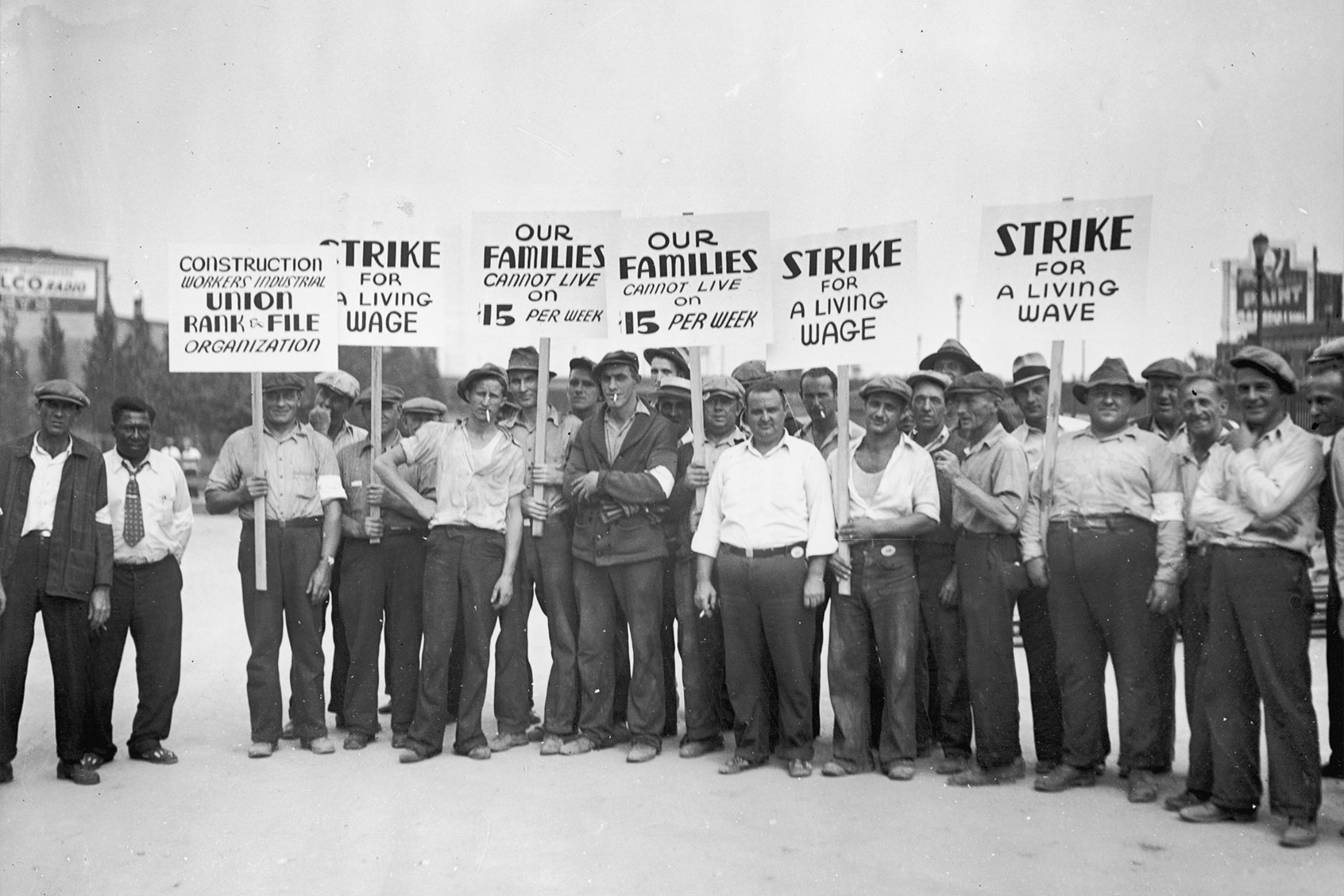 Full-length image of a group of strikers from the Construction Workers Union holding signs while picketing for higher wages. (Lambert/Getty Images)
