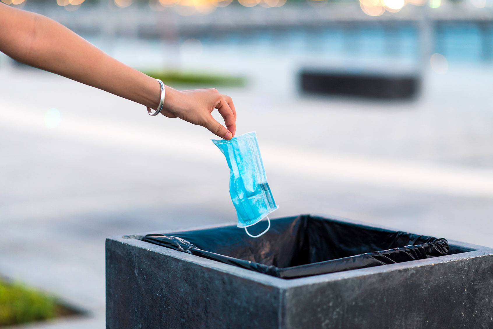 Woman throwing protective surgical mask into the garbage bin (Getty Images/Stefan Tomic)