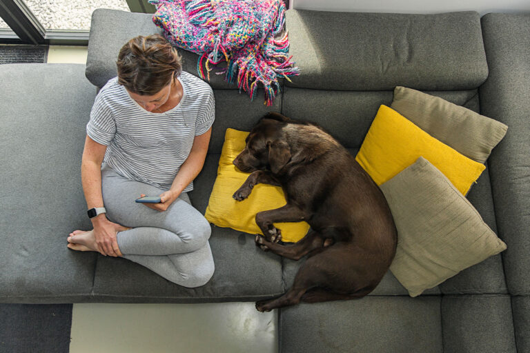 Woman sitting on the couch with her dog (Getty Images/Justin Paget)