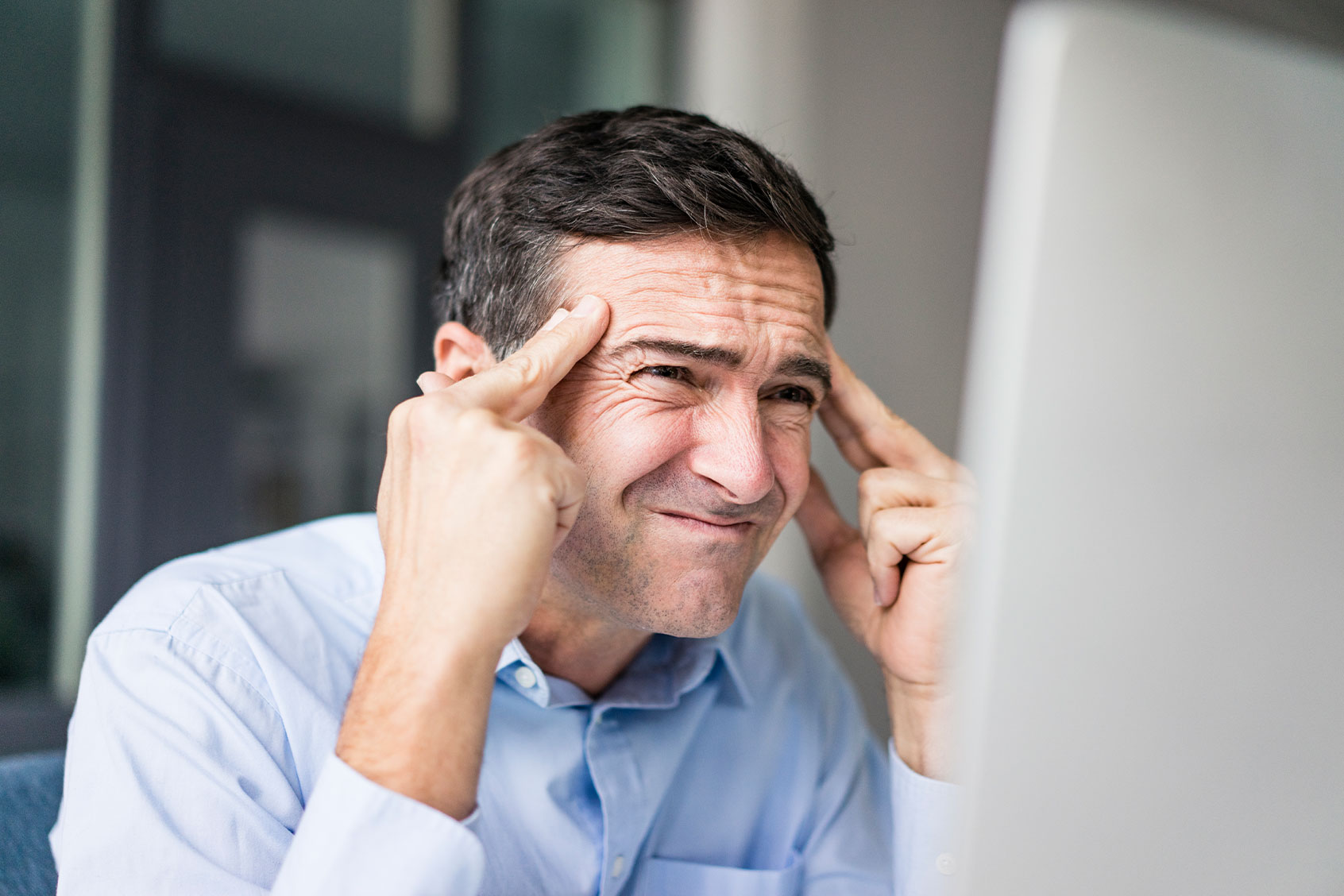 Grimacing businessman looking at computer screen (Getty Images/Westend61)