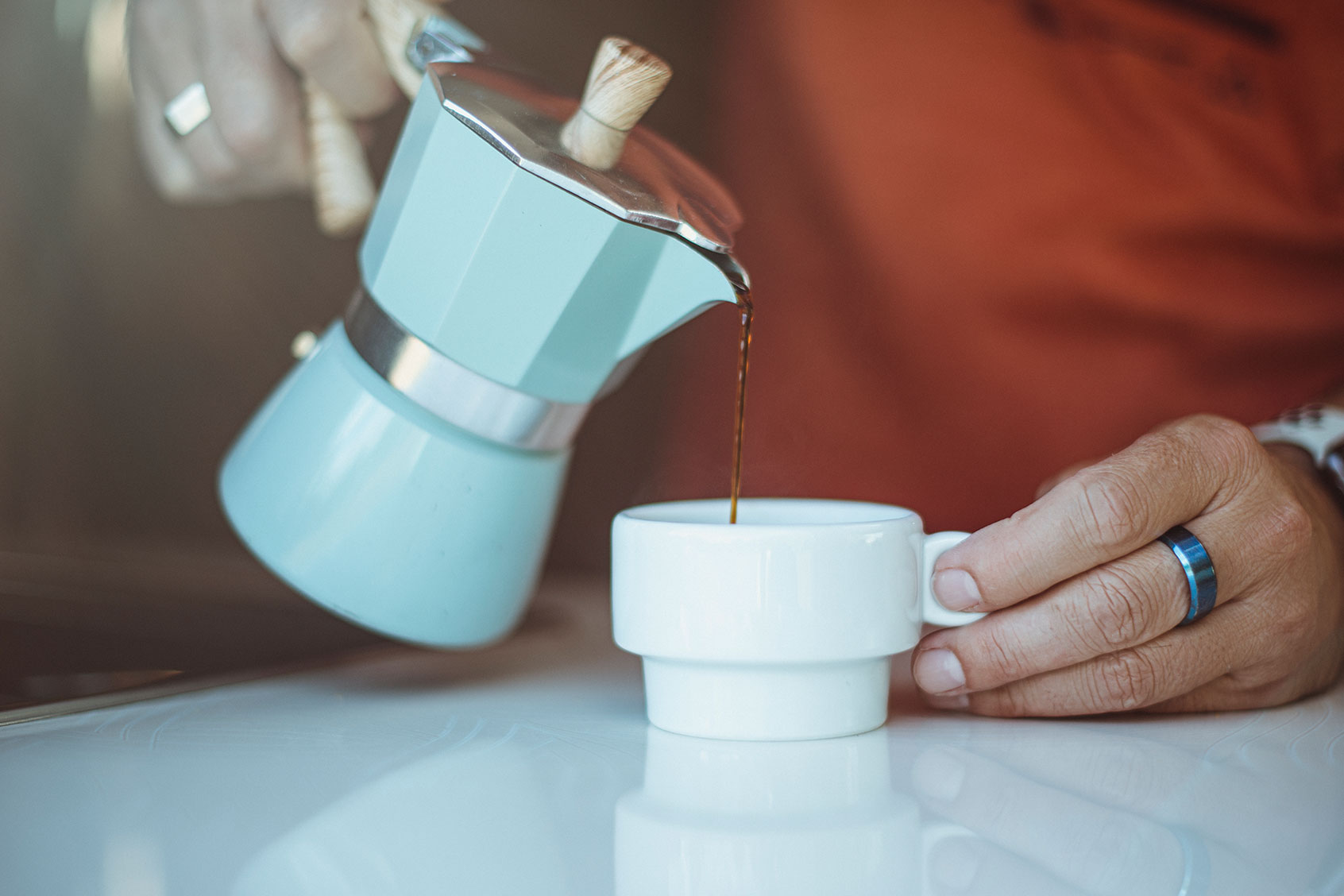 Man pouring coffee from a moka pot into a cup (Getty Images/NuriaE)