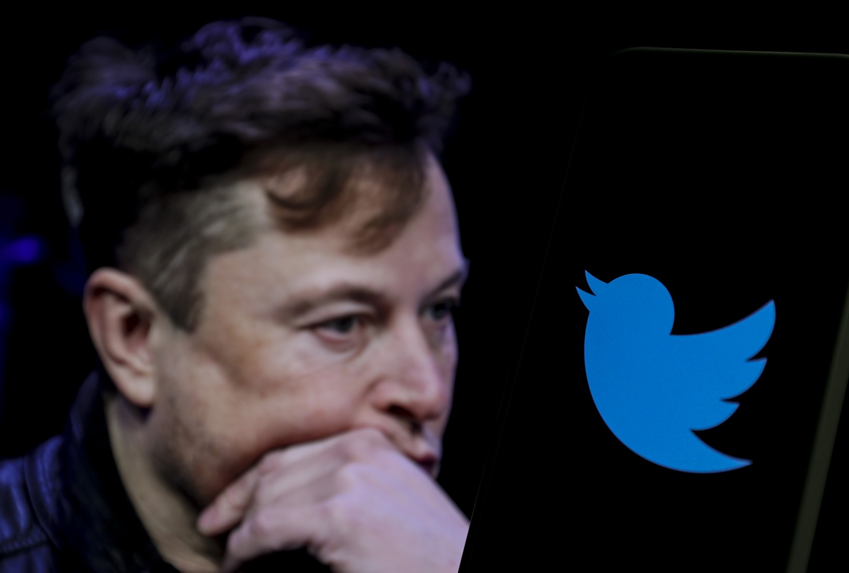 In this photo illustration, the image of Elon Musk is displayed on a computer screen and the logo of Twitter on a mobile phone. (Muhammed Selim Korkutata / Anadolu Agency via Getty Images)
