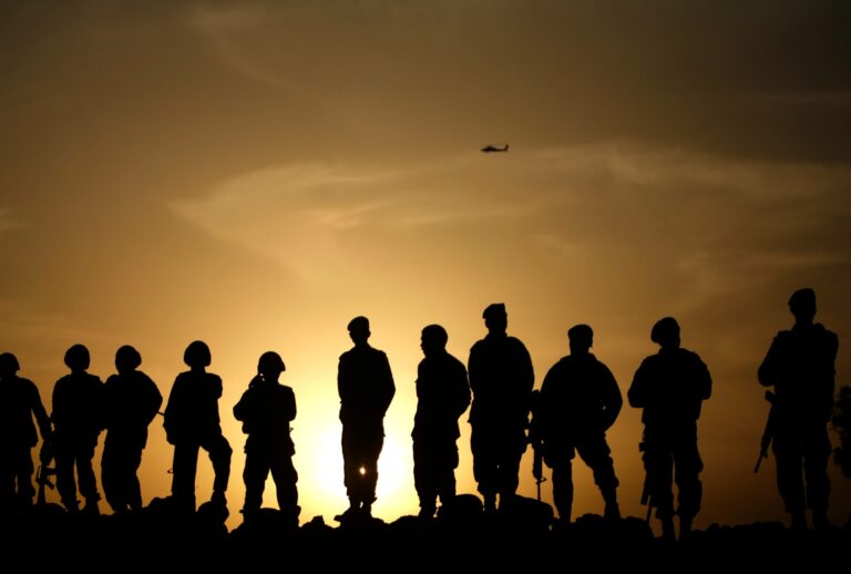 Afghan army commandos stand on a sand bank as a US Apache helicopter flies above on February 24, 2010. (PATRICK BAZ/AFP via Getty Images)