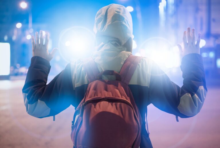 Male suspect arrested in the night, with police flashers behind him. (Михаил Руденко/Getty)