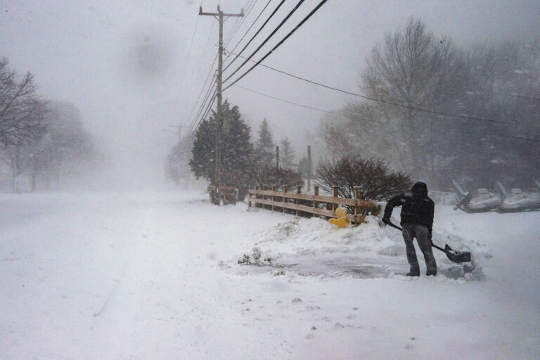 A man shovels snow in near whiteout conditions during a noreaster in Marshfield, Massachusetts, on January 29, 2022. (JOSEPH PREZIOSO/AFP via Getty Images)