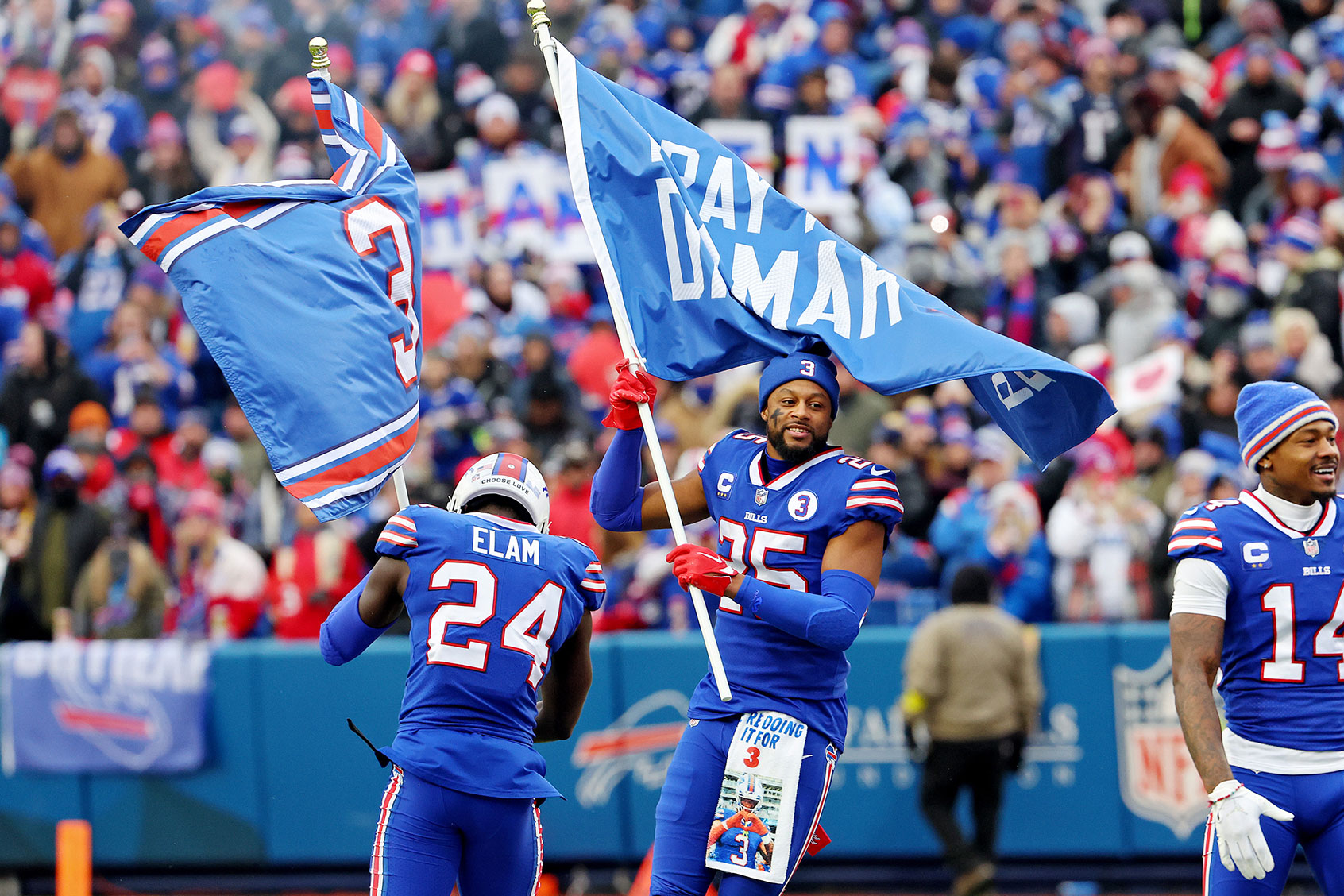 Kaiir Elam #24 and Taiwan Jones #25 of the Buffalo Bills wave flags in support of Buffalo Bills safety Damar Hamlin at Highmark Stadium on January 08, 2023 in Orchard Park, New York. (Timothy T Ludwig/Getty Images)