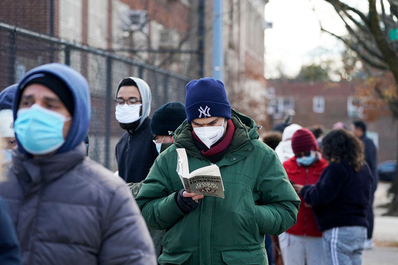 A man reads a book while waiting on line at a mobile Covid-19 test site. (BRYAN R. SMITH/AFP via Getty Images)
