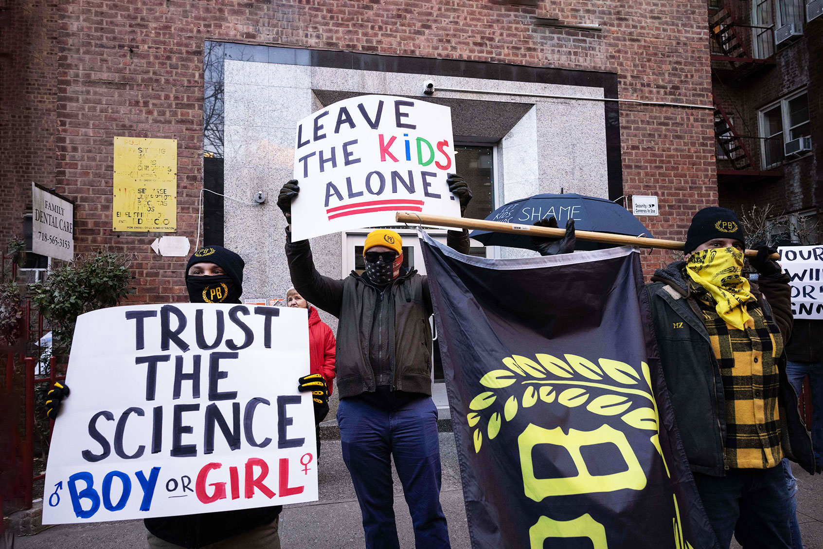Members of far-right group Proud Boys raise signs to protest against Drag Story Hour outside the Queens Public Library on December 29, 2022 in New York. (YUKI IWAMURA/AFP via Getty Images)