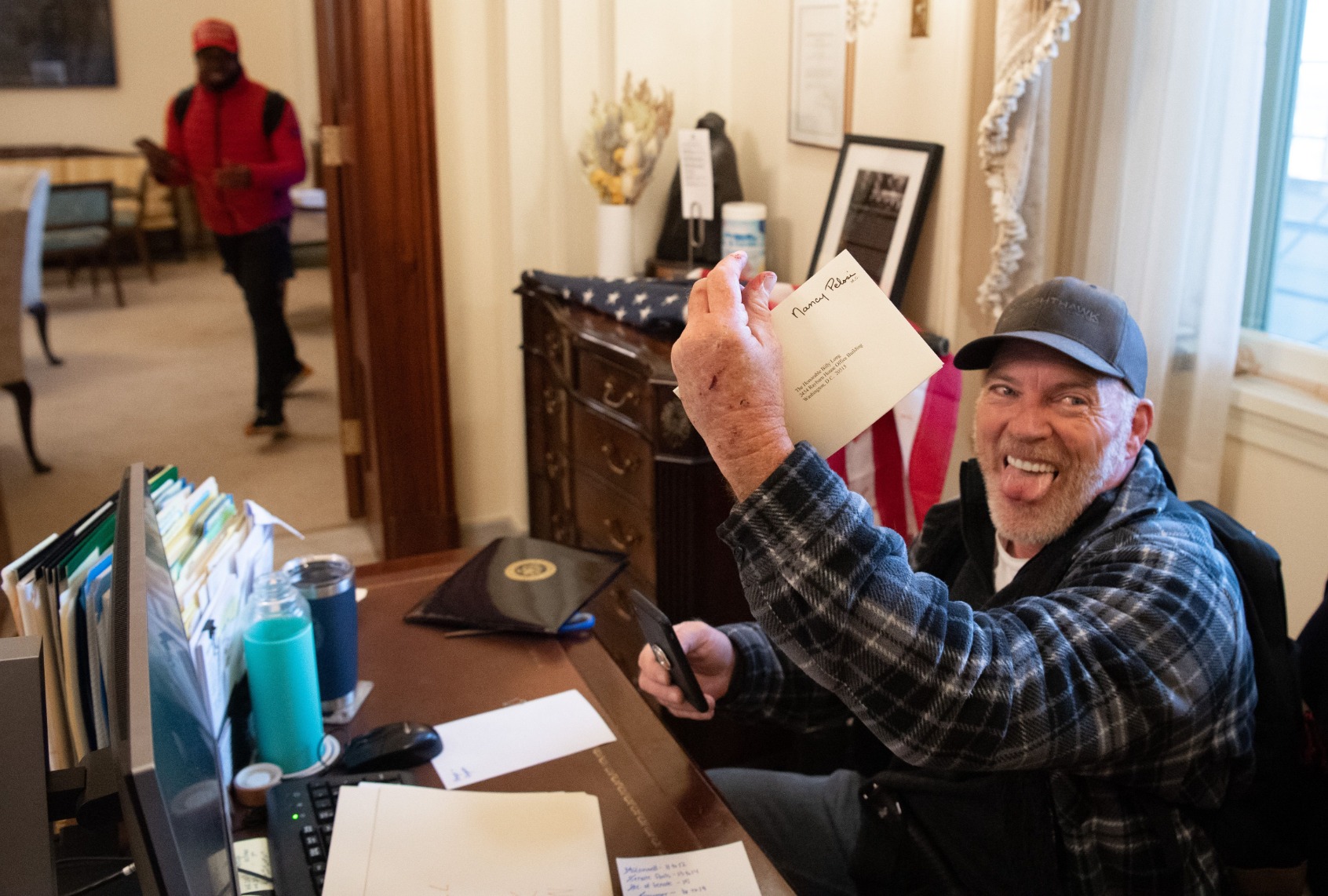 Richard Barnett, a supporter of US President Donald Trump, holds a piece of mail as he sits inside the office of US Speaker of the House Nancy Pelosi after protestors breached the US Capitol in the US Capitol in Washington, DC, January 6, 2021. (SAUL LOEB/AFP via Getty Images)