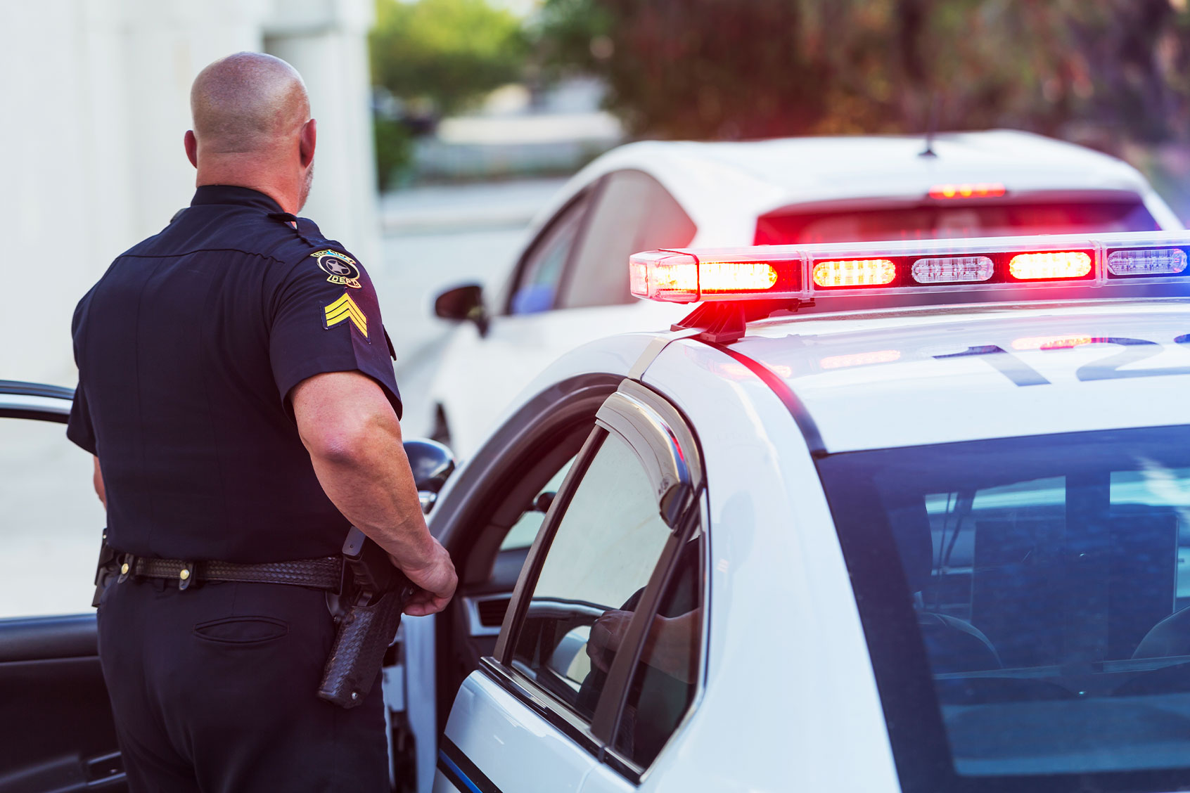 A policeman pulls over a driver, getting out of the police car to write a traffic ticket. (Getty Images/kali9)