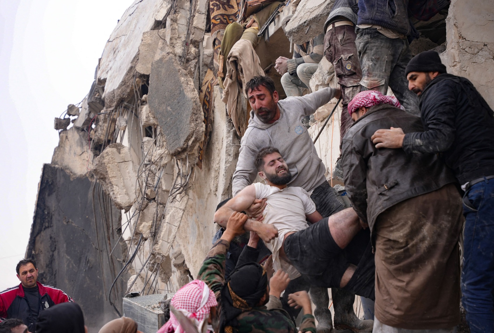 Residents retrieve an injured man from the rubble of a collapsed building following an earthquake in the town of Jandaris, in the countryside of Syria's northwestern city of Afrin in the rebel-held part of Aleppo province, on February 6, 2023. (RAMI AL SAYED/AFP via Getty Images)