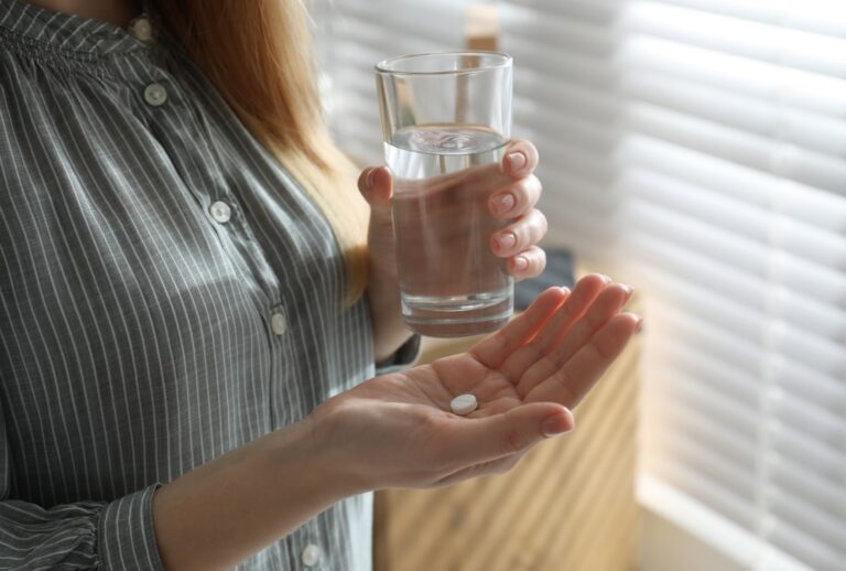 Woman with abortion pill and glass. (Liudmila Chernetska/Getty Images)