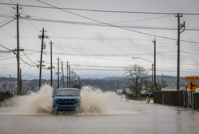 A truck drives through floodwaters from a breached levee on San Juan Road in Pajaro, Calif. on Tuesday, March 14, 2023. (Brontë Wittpenn/The San Francisco Chronicle via Getty Images)