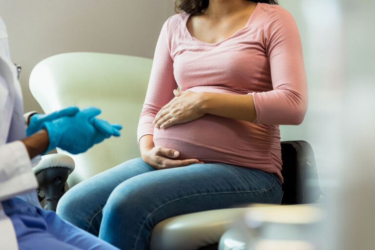 Doctor with protective gloves prepares to examine a pregnant woman (Getty Iimages/SDI Productions)