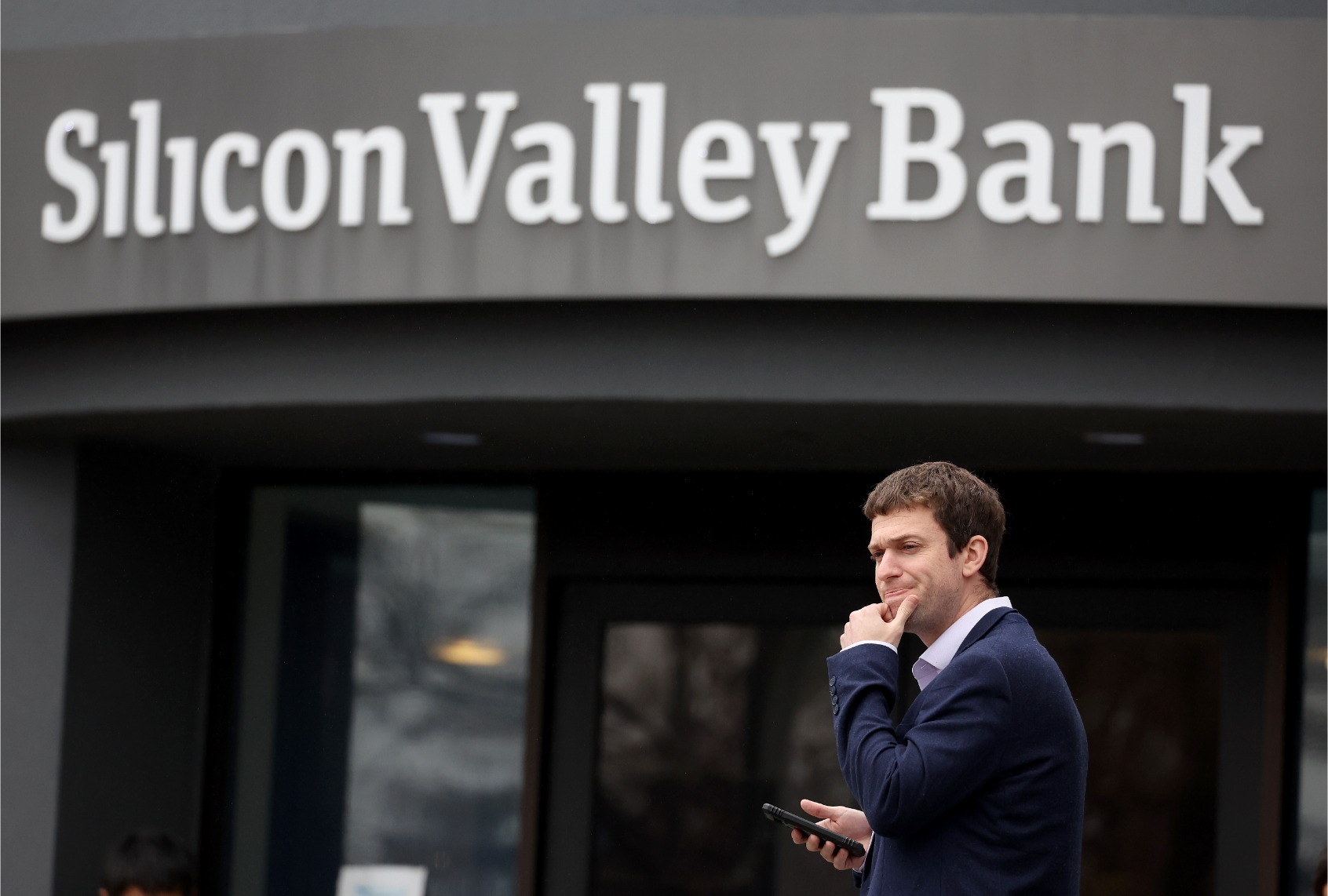 A customer stands outside of a shuttered Silicon Valley Bank (SVB) headquarters on March 10, 2023 in Santa Clara, California. (Justin Sullivan/Getty Images)