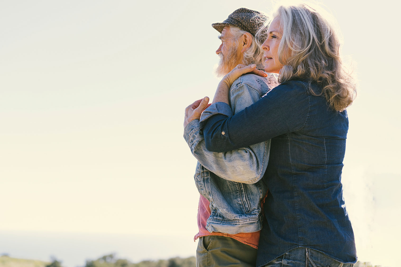 Side view of mature woman embracing man from behind against clear sky (Getty Images/The Good Brigade)