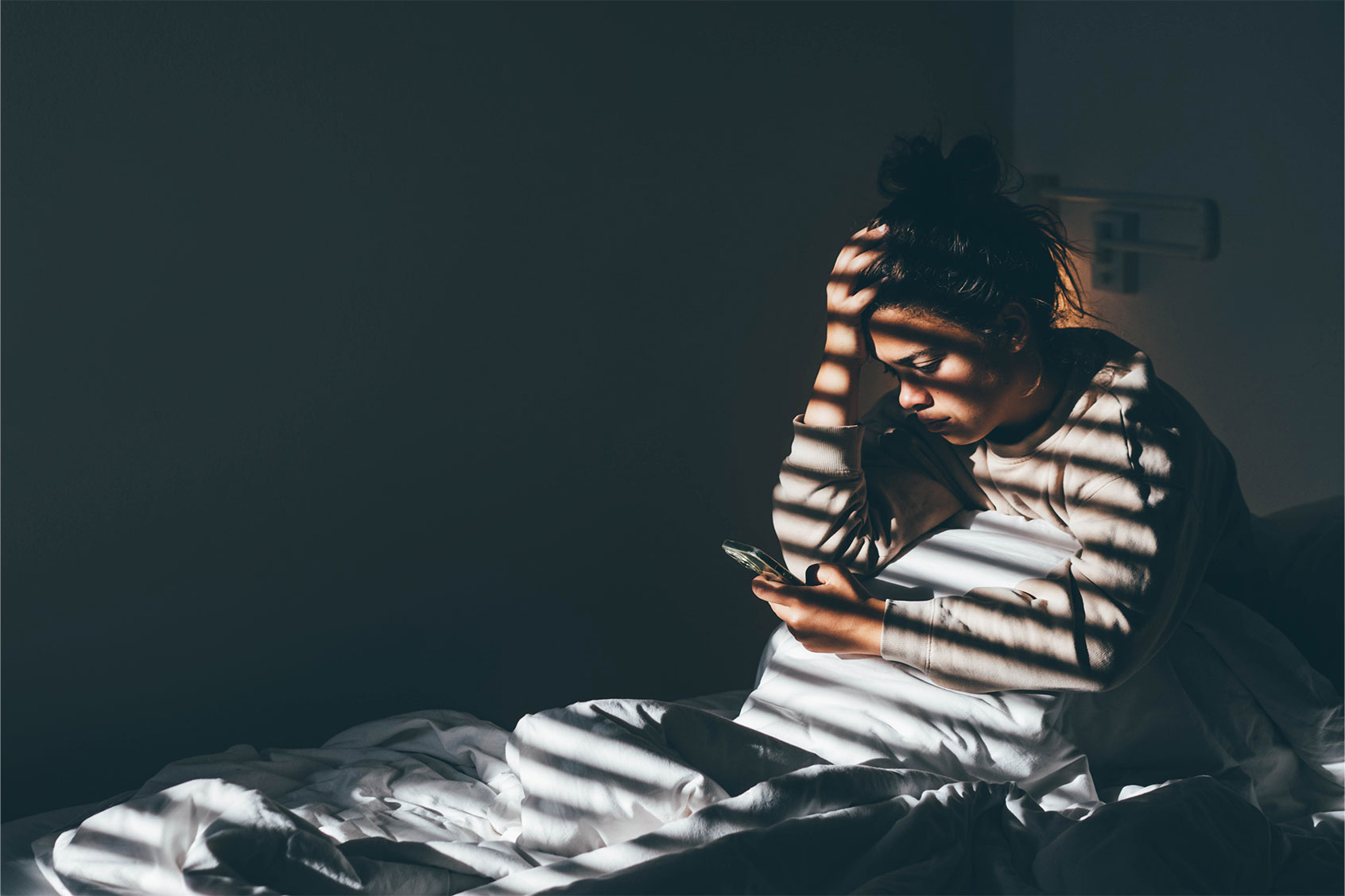 Worried young woman sitting on bed at home. (Getty Images/Maria Korneeva)