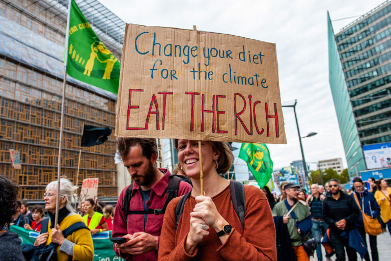 A protester holds a placard against the people with money during the climate change demonstration march. (Ana Fernandez/SOPA Images/LightRocket via Getty Images)
