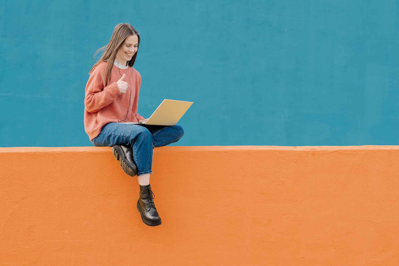 Woman showing a thumb up while on a computer (Getty Images/COROIMAGE)