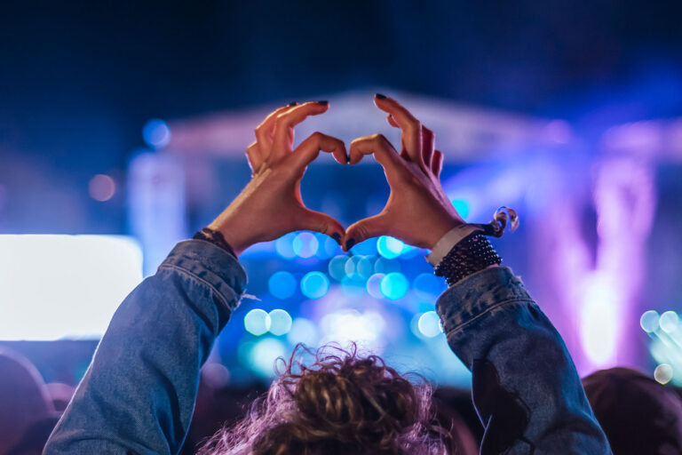 Woman making heart shape with hands at music event (Getty Images/Antonio Suarez Vega)