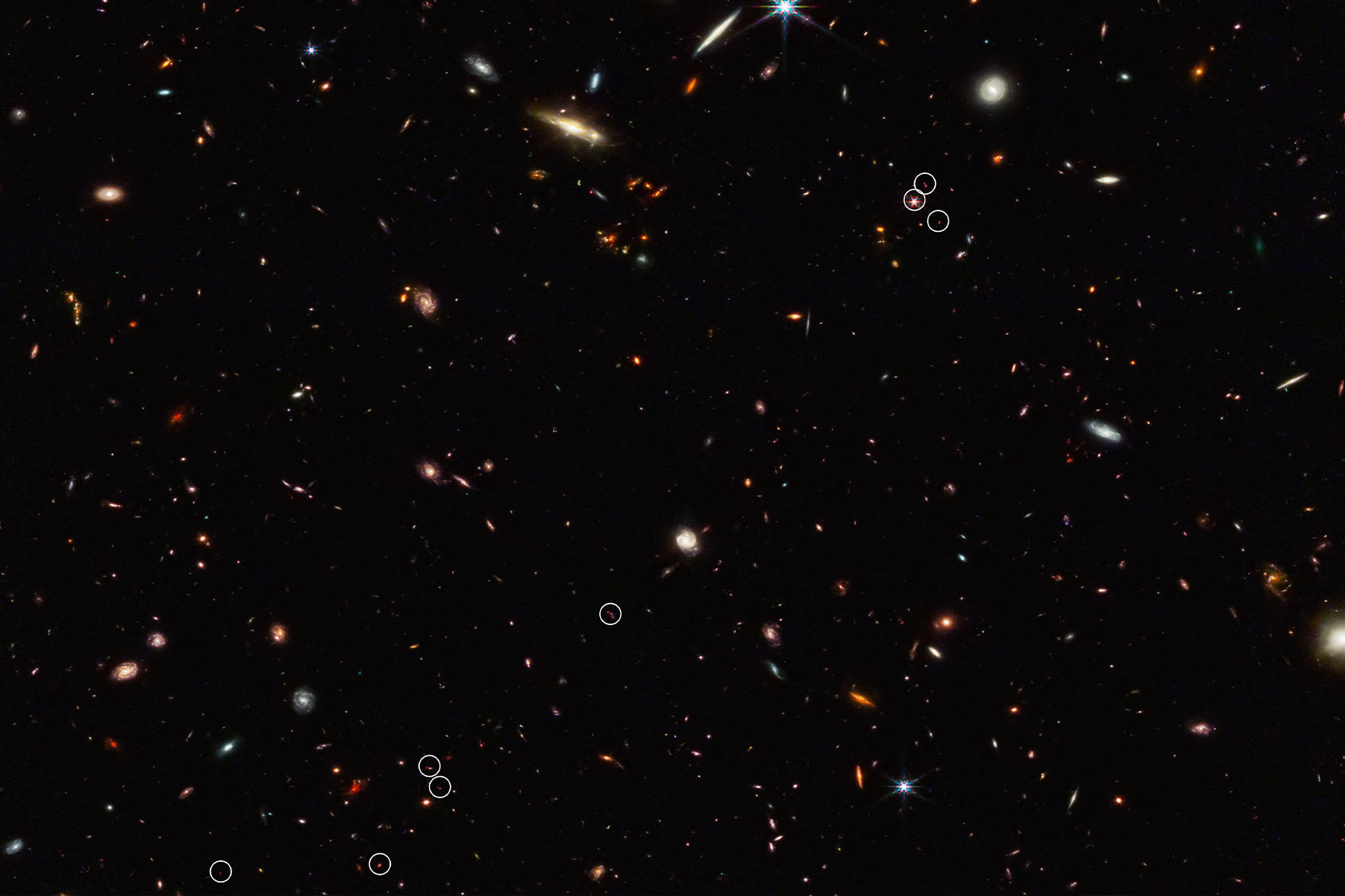This deep galaxy field from Webb’s NIRCam (Near-Infrared Camera) shows an arrangement of 10 distant galaxies marked by eight white circles in a diagonal, thread-like line. (Two of the circles contain more than one galaxy.) This 3 million light-year-long filament is anchored by a very distant and luminous quasar – a galaxy with an active, supermassive black hole at its core. (NASA, ESA, CSA, Feige Wang (University of Arizona), Joseph DePasquale (STScI))